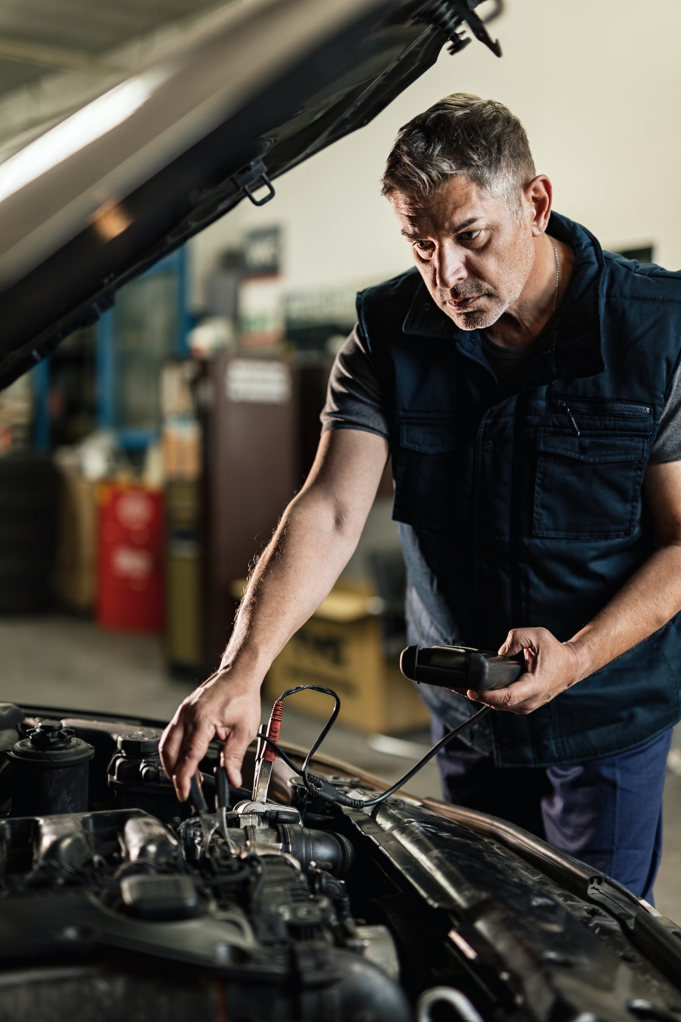 Mid adult mechanic working on car diagnostic in auto repair shop.